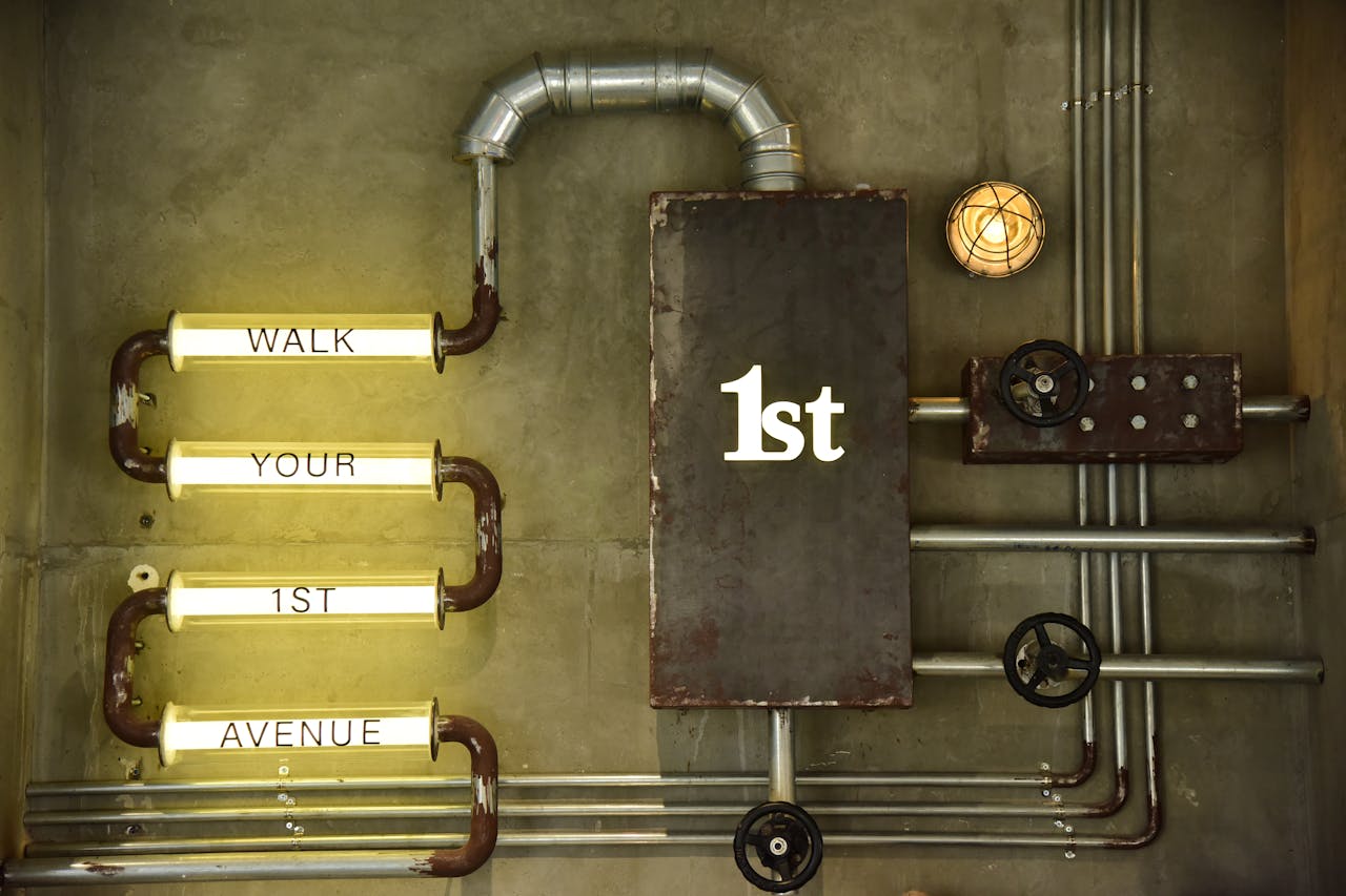 Home An artistic industrial wall design featuring metal pipes and illuminated words.