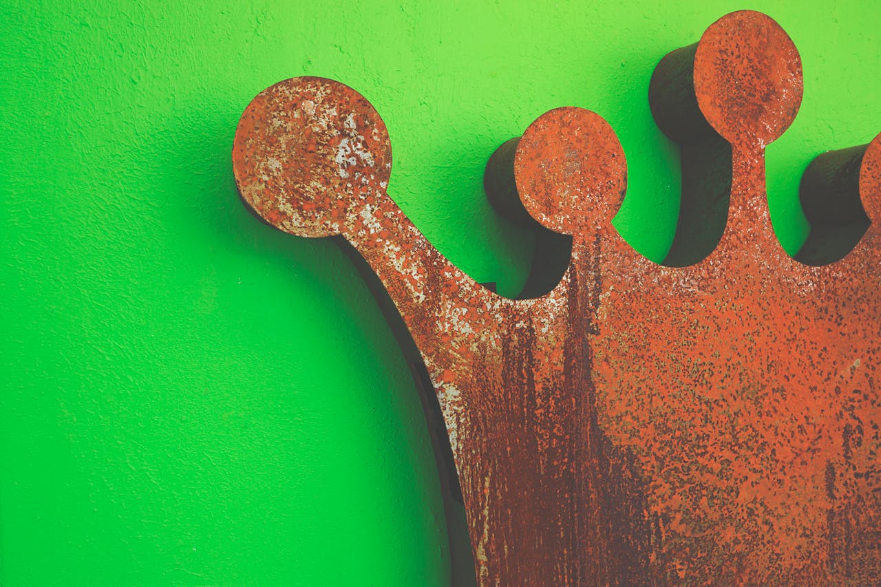 Home An artistic rusted iron crown set against a vivid green wall, showcasing texture and contrast.